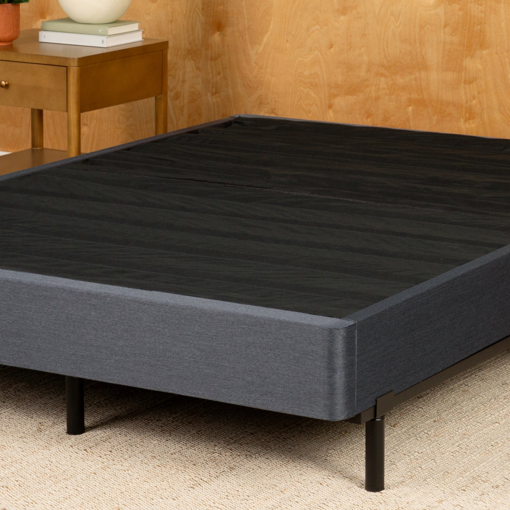 Tuft and Needle Gray bed frame with wooden headboard and nightstand in a room setting.