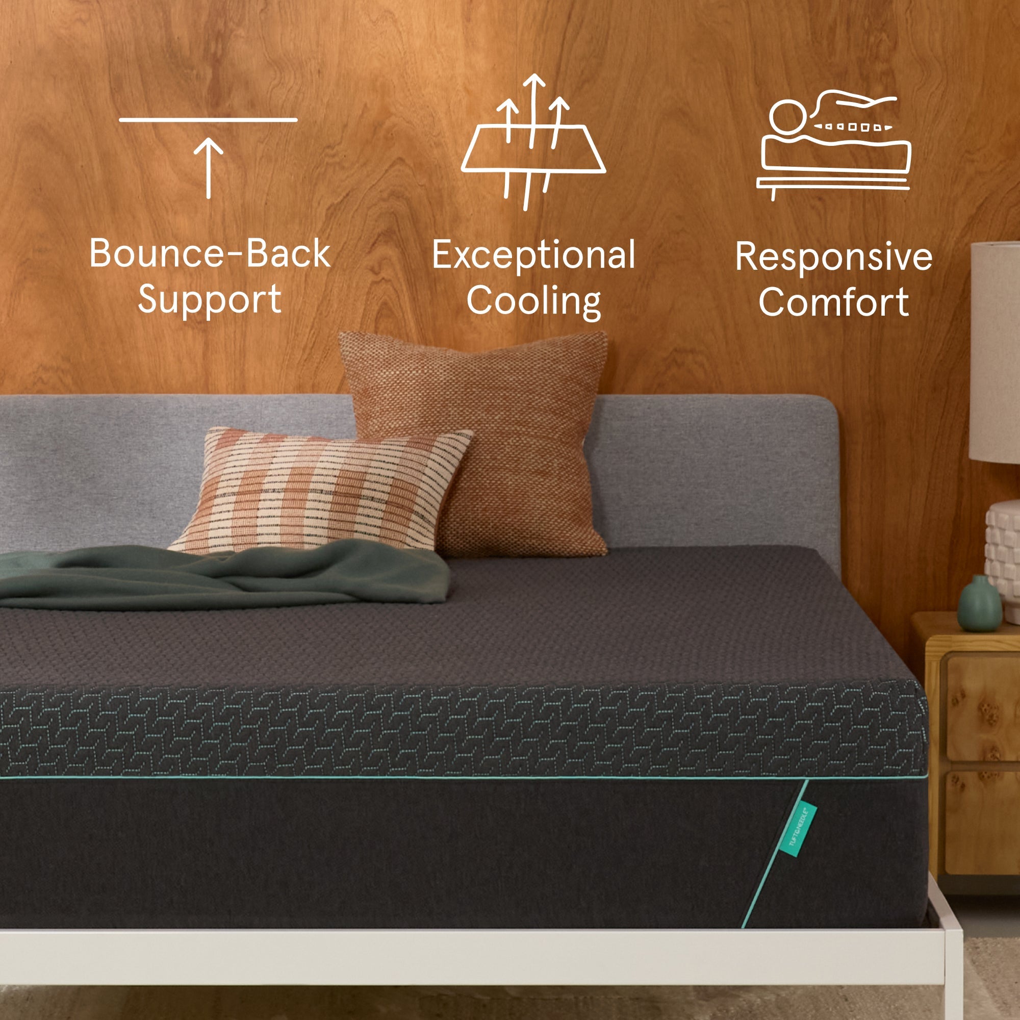 Tuft & Needle Mint Hybrid Mattress sitting in a brown bedframe with 2 pillows on top of it and a brown blanket with a chart on the wall showing icons reflecting Bounce-Back Support, Exceptional Cooling and Responsive Comfort