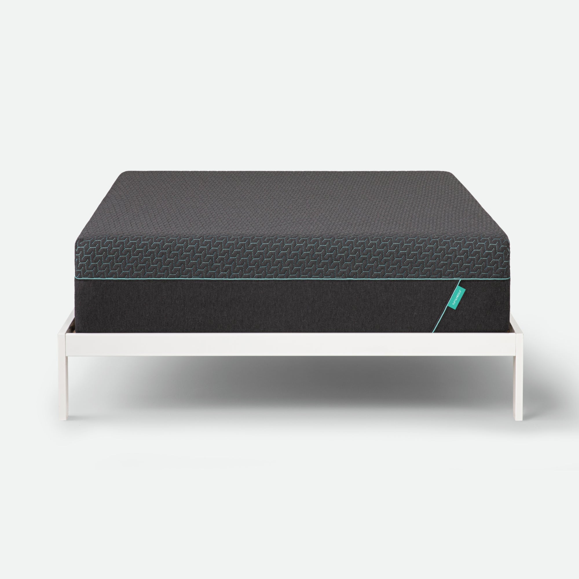 Tuft & Needle Black mattress on a white stand against a light gray background