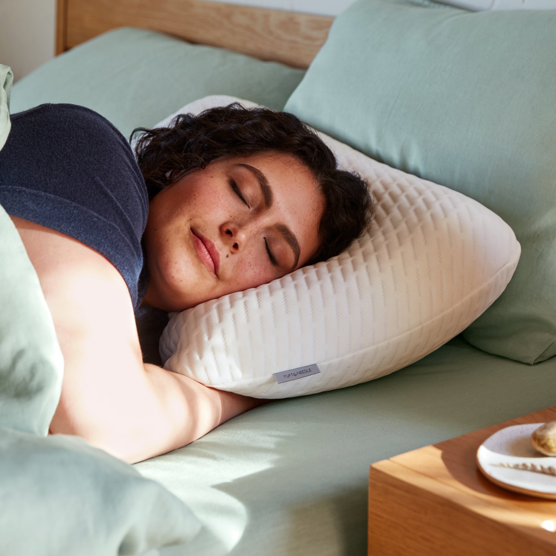 A woman sleeping in bed on the Tuft and Needle Original Foam Pillow